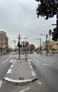 Photo Art Print of Jerusalem Avenue in TLV, showing street corner with traffic lights, signs, and construction cranes above cloudy sky.